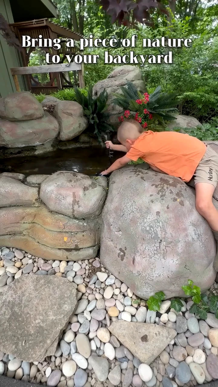 A child reaches toward the water in Megan's garden