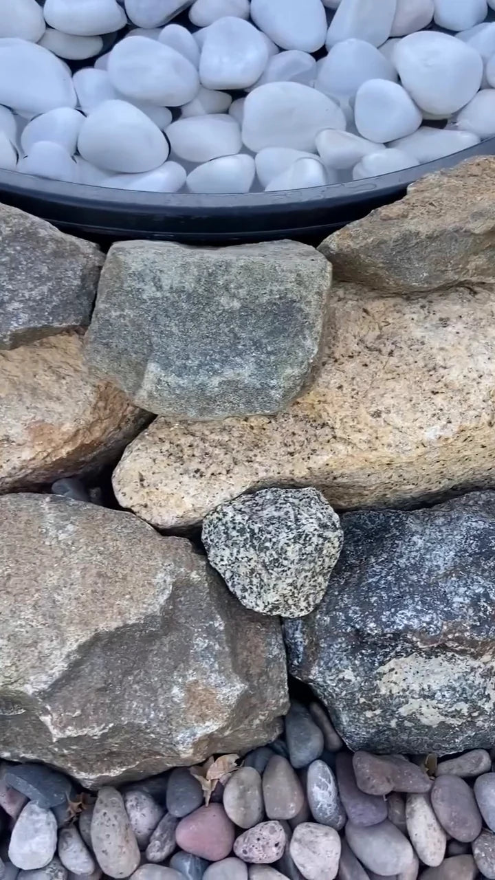 White pebbles cover the basin inside the stone border.
